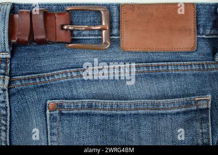 Etiquette en cuir vide et boucle de ceinture sur un Jean bleu, modèle gros plan Banque D'Images