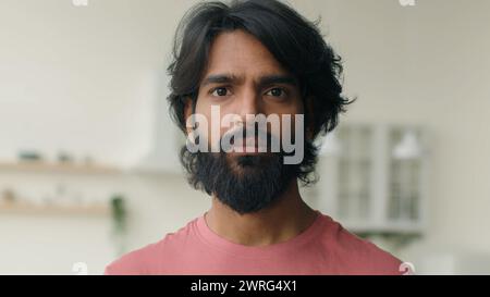 Gros plan sur la tête d'un musulman arabe debout dans la salle de cuisine. Portrait indien homme barbu ethnique sérieux regardant la caméra homme d'affaires calme seul Banque D'Images