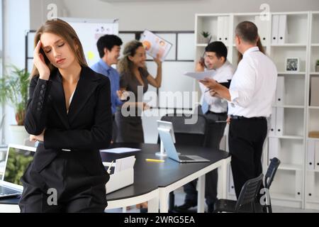 Jeune femme d'affaires souffrant de collègues bruyants dans le bureau Banque D'Images