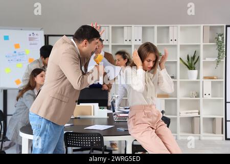 Jeune femme d'affaires souffrant de collègues bruyants dans le bureau Banque D'Images