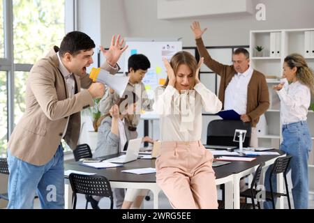 Jeune femme d'affaires souffrant de collègues bruyants dans le bureau Banque D'Images