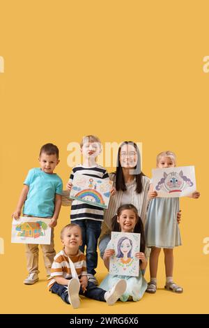 Petits enfants avec des dessins sur fond jaune Banque D'Images