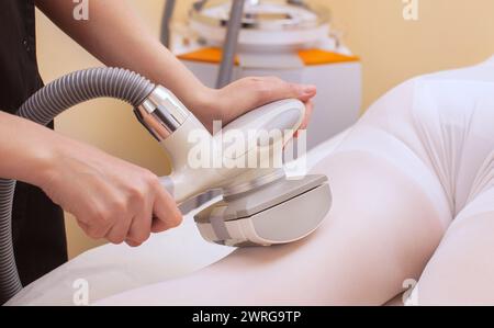 Le masseur fait un massage matériel sur les jambes du patient dans un costume blanc, gros plan dans un salon de beauté. Banque D'Images