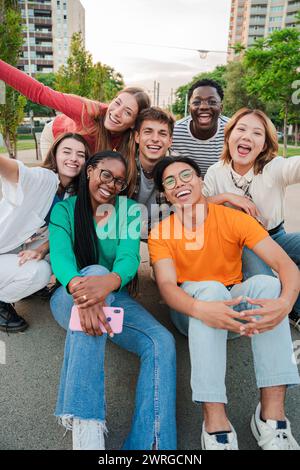 Portrait vertical d'amis heureux riant. Grand groupe de jeunes adultes vrais gens souriants et s'amusant à l'extérieur pendant les vacances. Des étudiants adolescents universitaires sur un rassemblement social. Adolescents multiraciaux. Photo de haute qualité Banque D'Images