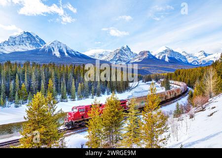 BANFF, CANADA - FÉV. 22, 2024 : le train de marchandises du chemin de fer canadien Pacifique traverse la courbe de Morant dans la vallée de la Bow, dans le parc national Banff, pendant le Wint Banque D'Images