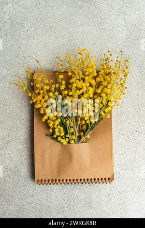 Vue aérienne d'un bouquet de fleurs de mimosa jaunes nichées dans un bloc-notes Banque D'Images