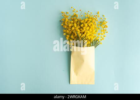 Vue aérienne d'un bouquet de fleurs de mimosa jaune dans une enveloppe sur une table Banque D'Images