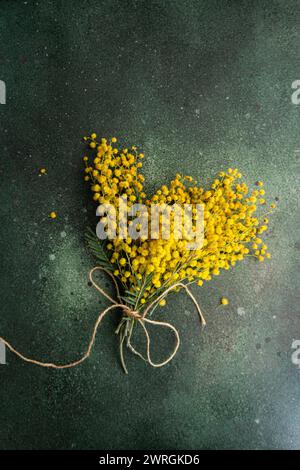 Vue aérienne d'un bouquet de tiges de mimosa jaune fraîchement cueillies attachées avec de la ficelle sur une table Banque D'Images