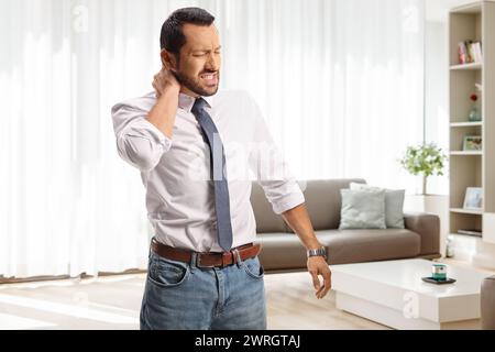 Jeune homme avec douleur dans le cou rentrant à la maison après une longue journée bien remplie au travail Banque D'Images