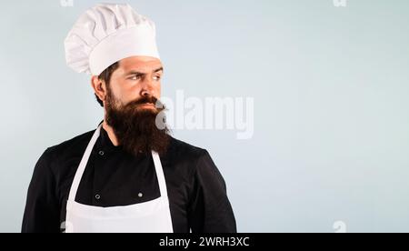 Portrait d'homme barbu sérieux en uniforme de chef. Chef professionnel, cuisinier ou boulanger regardant loin sur l'espace de copie pour la publicité. Chef confiant en blanc Banque D'Images