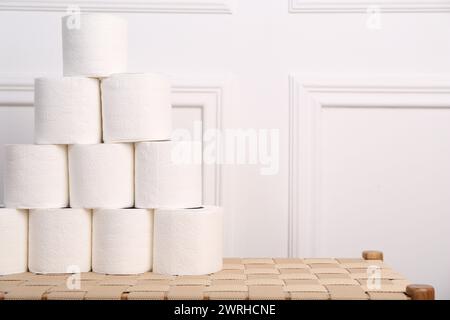 Pyramide de rouleaux de papier toilette sur banc en osier. Espace pour le texte Banque D'Images