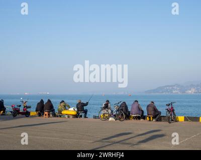 Résidents locaux sur la pêche en mer amateur. Le dos des pêcheurs sur la jetée. Loisirs en plein air. Passe-temps pour hommes. Pêche passive Banque D'Images