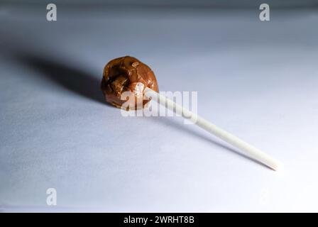 Une sucette en chocolat alléchante avec une surface lisse et brillante, capturée avec netteté sur un fond blanc Banque D'Images