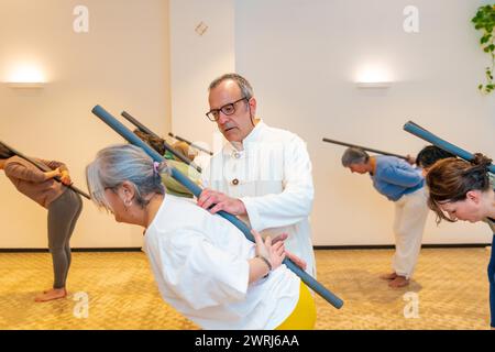 Les membres de la classe de Qi gong utilisent un tube pour étirer le dos avec les conseils d'un instructeur masculin Banque D'Images