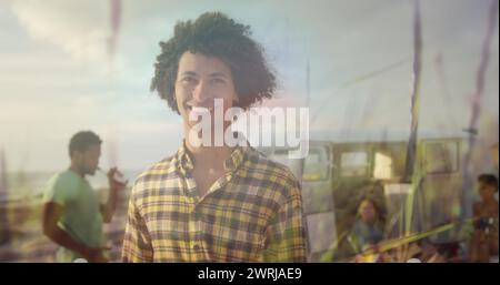 Image d'homme biracial souriant avec des amis à la plage sur l'herbe Banque D'Images