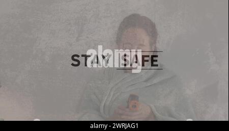 Image de slogans de coronavirus sur une femme caucasienne allongée dans son lit et prenant de la température Banque D'Images