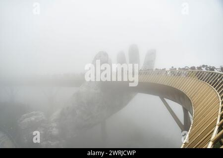 Danang, Vietnam - 27 juin 2023 : le pont d'or est soulevé par deux mains géantes dans la station touristique sur la colline de Ba Na Banque D'Images