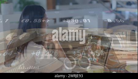 Jeune femme biraciale analysant des données financières superposant l'image Banque D'Images