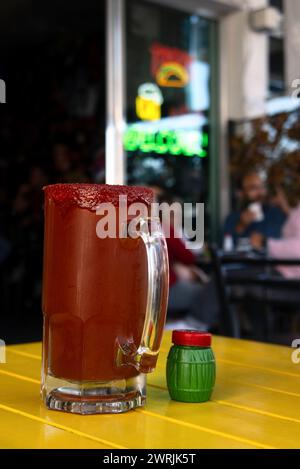 Une Michelada, boisson mexicaine de bière, clamato, salda, citron et chamoy, avec un espace pour le texte Banque D'Images