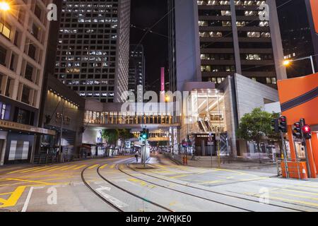 Hong Kong - 19 juillet 2017 : paysage urbain nocturne du quartier central, vue en perspective sur les rails du tramway, les gens ordinaires marchent dans la rue Banque D'Images