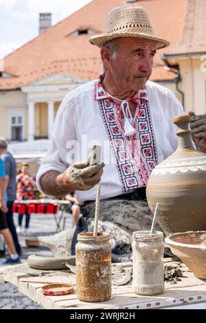 Sibiu City, Roumanie - 03 septembre 2023. Un potier plus âgé façonnant un pot en argile sur une roue de poterie à la foire des potiers de Sibiu, Roumanie Banque D'Images