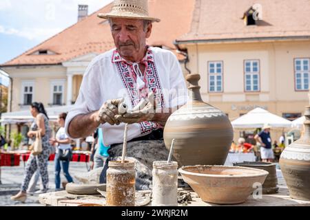 Sibiu City, Roumanie - 03 septembre 2023. Un potier plus âgé façonnant un pot en argile sur une roue de poterie à la foire des potiers de Sibiu, Roumanie Banque D'Images