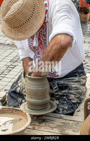 Sibiu City, Roumanie - 03 septembre 2023. Un potier plus âgé façonnant un pot en argile sur une roue de poterie à la foire des potiers de Sibiu, Roumanie Banque D'Images