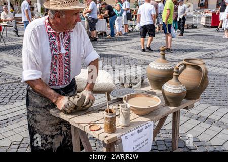 Sibiu City, Roumanie - 03 septembre 2023. Un potier plus âgé façonnant un pot en argile sur une roue de poterie à la foire des potiers de Sibiu, Roumanie Banque D'Images