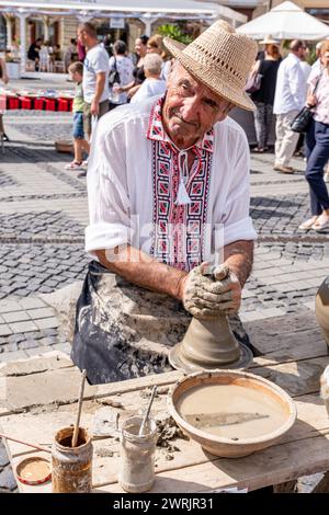 Sibiu City, Roumanie - 03 septembre 2023. Un potier plus âgé façonnant un pot en argile sur une roue de poterie à la foire des potiers de Sibiu, Roumanie Banque D'Images