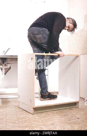 Homme plus âgé démontant la cuisine de l'appartement hors service Banque D'Images