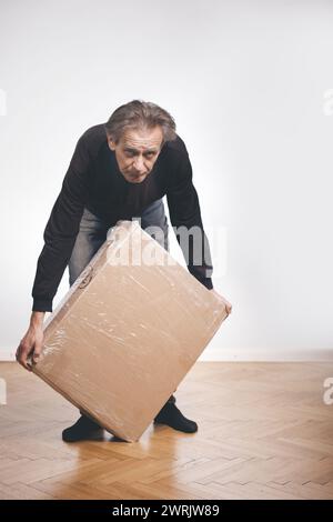 Homme déballant la boîte de papier avec un ensemble de trois tiroirs en bois laminé Banque D'Images