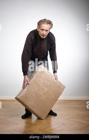 Homme déballant la boîte de papier avec un ensemble de trois tiroirs en bois laminé Banque D'Images