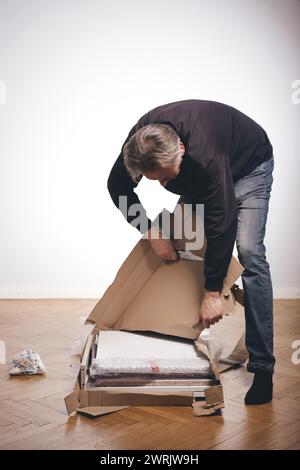 Homme déballant la boîte de papier avec un ensemble de trois tiroirs en bois laminé Banque D'Images