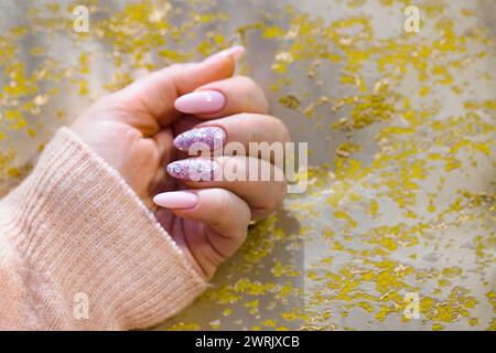 Une main de femme méticuleusement entretenue avec de superbes ongles en gel rose. Les ongles sont parfaitement peints, avec deux ornés de style, multicolores Banque D'Images