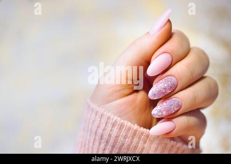 Une main de femme méticuleusement entretenue avec de superbes ongles en gel rose. Les ongles sont parfaitement peints, avec deux ornés de style, multicolores Banque D'Images