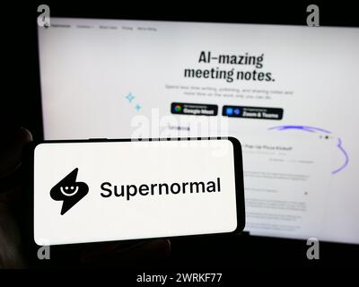 Personne tenant un smartphone avec le logo de la société américaine ai Supernormal technologies Inc en face du site Web. Concentrez-vous sur l'affichage du téléphone. Banque D'Images
