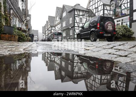 Schmuddeliges und ungemuetliches ungemütliches Wetter im Siegerland. Tristesse in der Altstadt von Freudenberg, einem Beliebten Touristenziel, Reiseziel in Suedwestfalen Südwestfalen. Die Fachwerkhaeuser spiegeln sich in einer Pfuetze Pfütze Winter im Siegerland AM 13.03.2024 in Freudenberg/Deutschland. *** Mauvais temps sale et inconfortable à Siegerland Tristesse dans la vieille ville de Freudenberg, une destination touristique populaire en Westphalie du Sud Westphalie du Sud les maisons à colombages se reflètent dans une flaque d'eau hiver à Siegerland le 13 03 2024 à Freudenberg Allemagne Banque D'Images