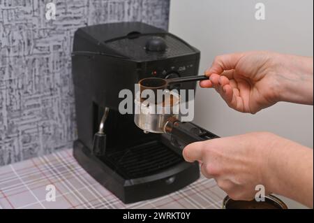 les mains des femmes versent le café dans la machine à café Banque D'Images