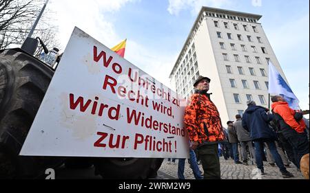 Erfurt, Allemagne. 13 mars 2024. Des manifestants se tiennent devant le parlement de Thuringe avant le début de la session de trois jours. Un panneau dit "là où l'injustice devient loi, la résistance devient devoir!". Les thèmes du débat d'une heure comprennent, par exemple, le travail obligatoire de service public pour les demandeurs d'asile et l'extension de l'infrastructure ferroviaire de Thuringe. Crédit : Martin Schutt/dpa/Alamy Live News Banque D'Images