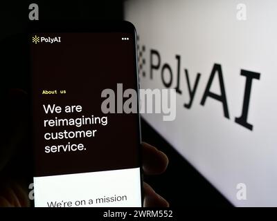 Personne tenant un smartphone avec le site Web de la société d'intelligence artificielle conversationnelle PolyAI Ltd. avec logo. Concentrez-vous sur le centre de l'écran du téléphone. Banque D'Images