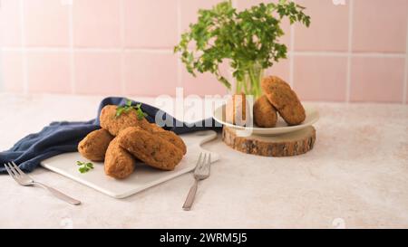 Boulettes de morue, ou « bolinhos de bacalhau » et feuilles de persil sur des plats en céramique blanche dans un comptoir de cuisine. Banque D'Images