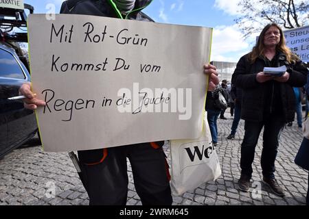 Erfurt, Allemagne. 13 mars 2024. Des manifestants se tiennent devant le parlement de Thuringe avant le début de la session de trois jours. Une affiche dit « avec rouge-vert, vous passez de la pluie à la boue ». Les thèmes du débat d'une heure comprennent, par exemple, le travail obligatoire de service public pour les demandeurs d'asile et l'extension de l'infrastructure ferroviaire de Thuringe. Crédit : Martin Schutt/dpa/Alamy Live News Banque D'Images