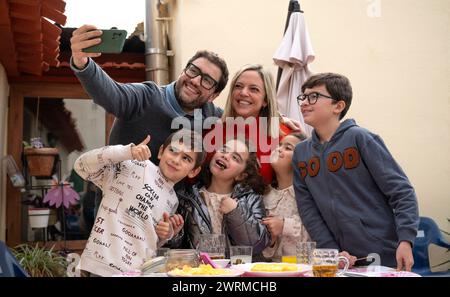 Une famille heureuse de six sourires pour un selfie autour d'une table avec de la nourriture lors d'une réunion de famille en plein air. Banque D'Images