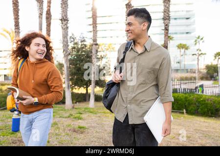 Divers étudiants rient et conversent dehors avec un ordinateur portable et une bouteille réutilisable Banque D'Images
