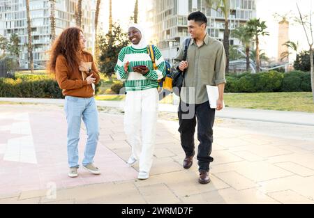 Un groupe multiethnique de jeunes adultes, y compris une femme afro-américaine, un homme hispanique et une femme aux cheveux bouclés, engagés dans une conversation animée Banque D'Images