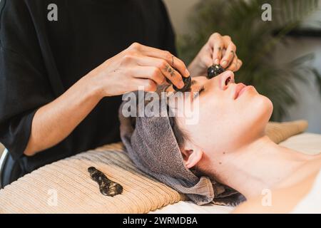 Une personne reçoit un soin du visage gua Sha apaisant dans un cadre de spa serein Banque D'Images