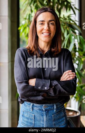 Une femme professionnelle debout, les bras croisés, souriant à la caméra sur fond naturel. Banque D'Images