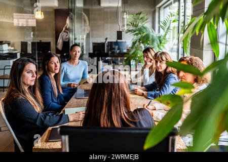 Un groupe de femmes entrepreneurs est activement engagé dans une réunion d'affaires à l'intérieur d'un espace de bureau moderne, démontrant le travail d'équipe et la collaboration entre eux Banque D'Images
