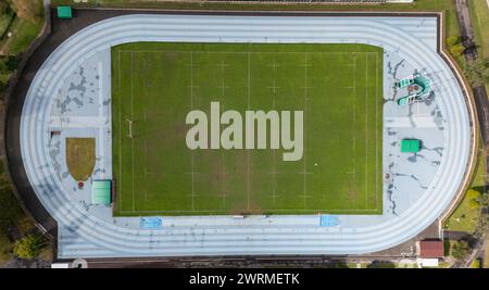 Prise de vue par drone capturant la vue de haut en bas d'un complexe sportif comprenant une piste, un terrain et les installations environnantes. Banque D'Images