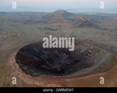 Vue aérienne de Calderon Hondo, un impressionnant cratère volcanique à Fuerteventura, photographié au coucher du soleil avec une vue dégagée sur le paysage environnant. Banque D'Images